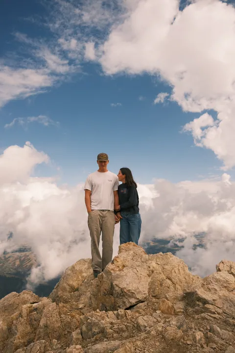 Friends on a summit rock above the clouds