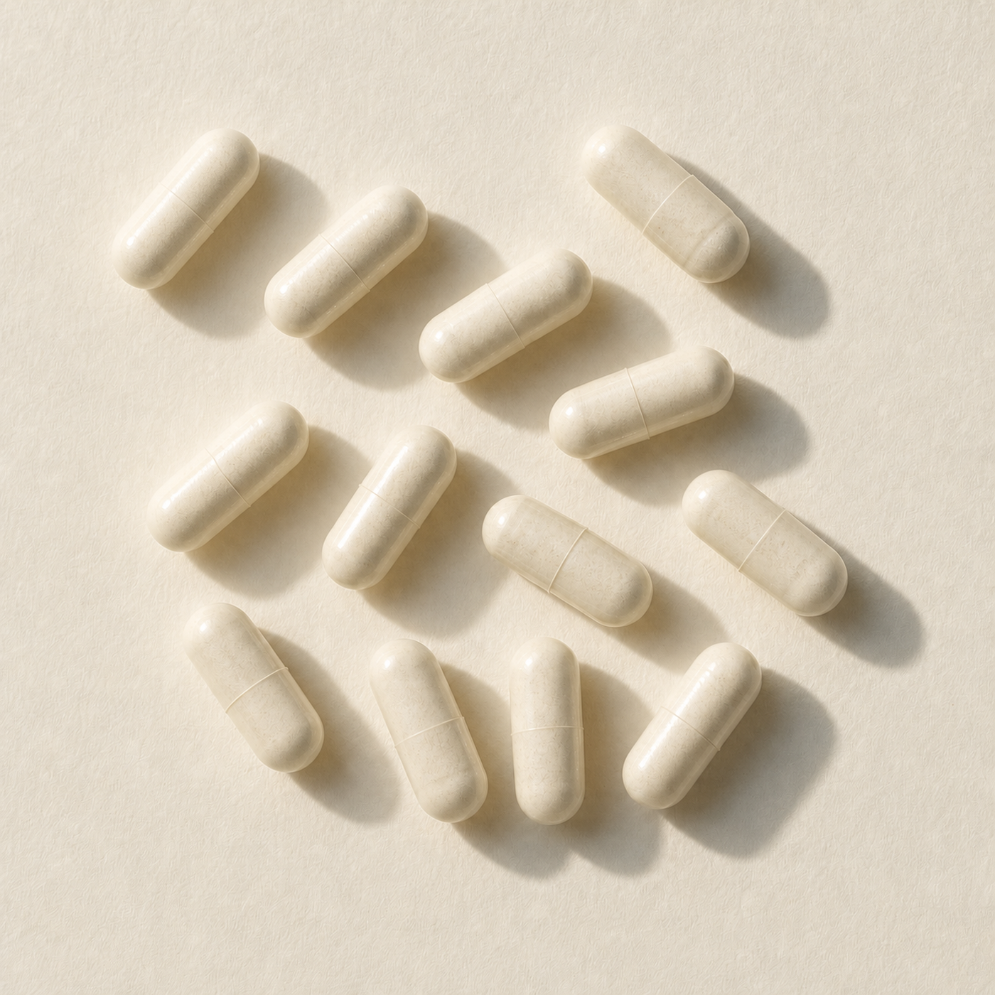 Twelve vegetable capsules on warm ivory paper